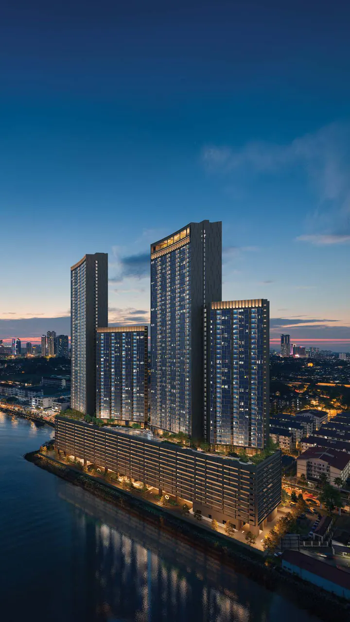 Dusk on the Johor shore: the four curved crowns of The Eclipse lit above the water, Johor Bahru beyond (photograph with CGI of the proposed towers)